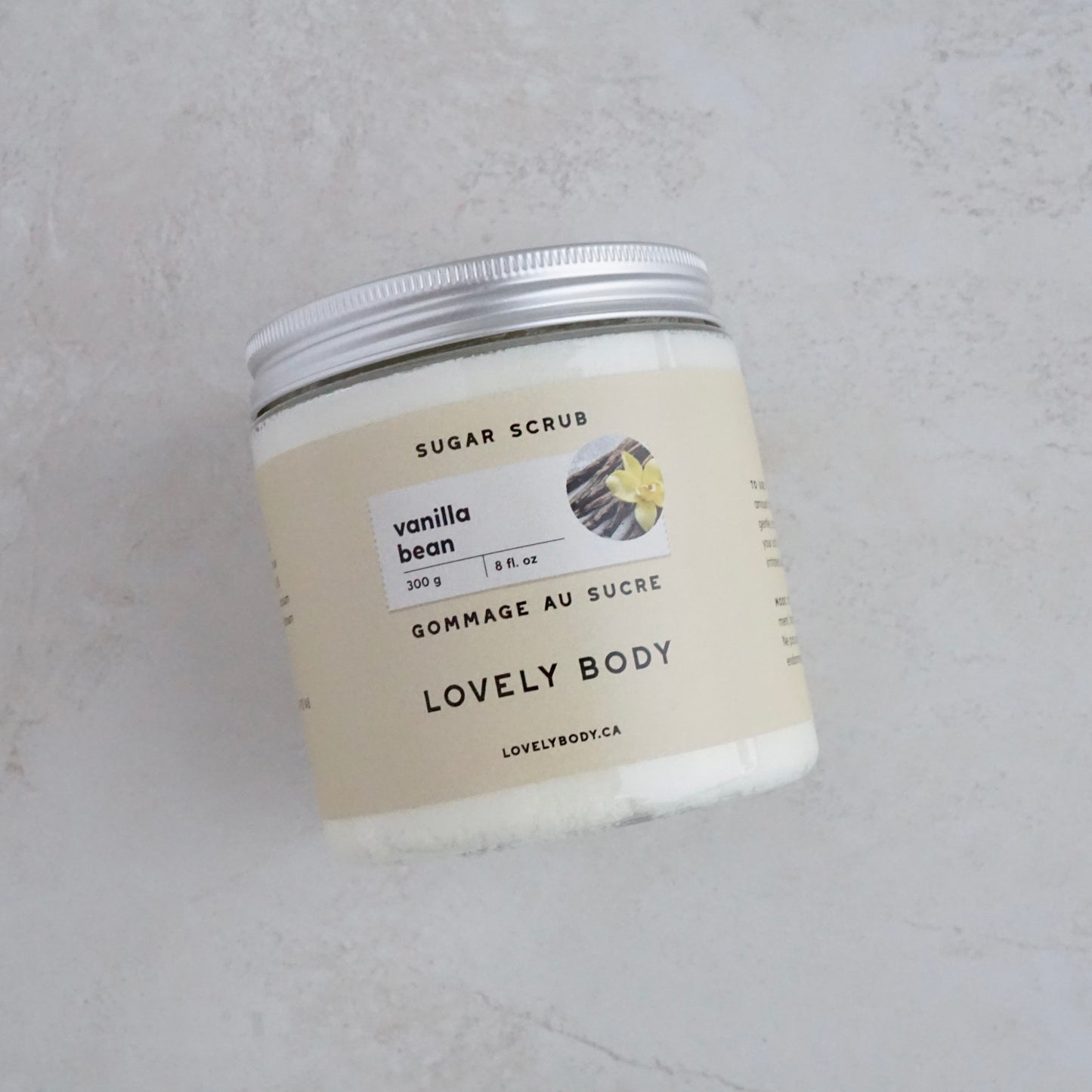 A jar of cream coloured scrub on neutral tile background