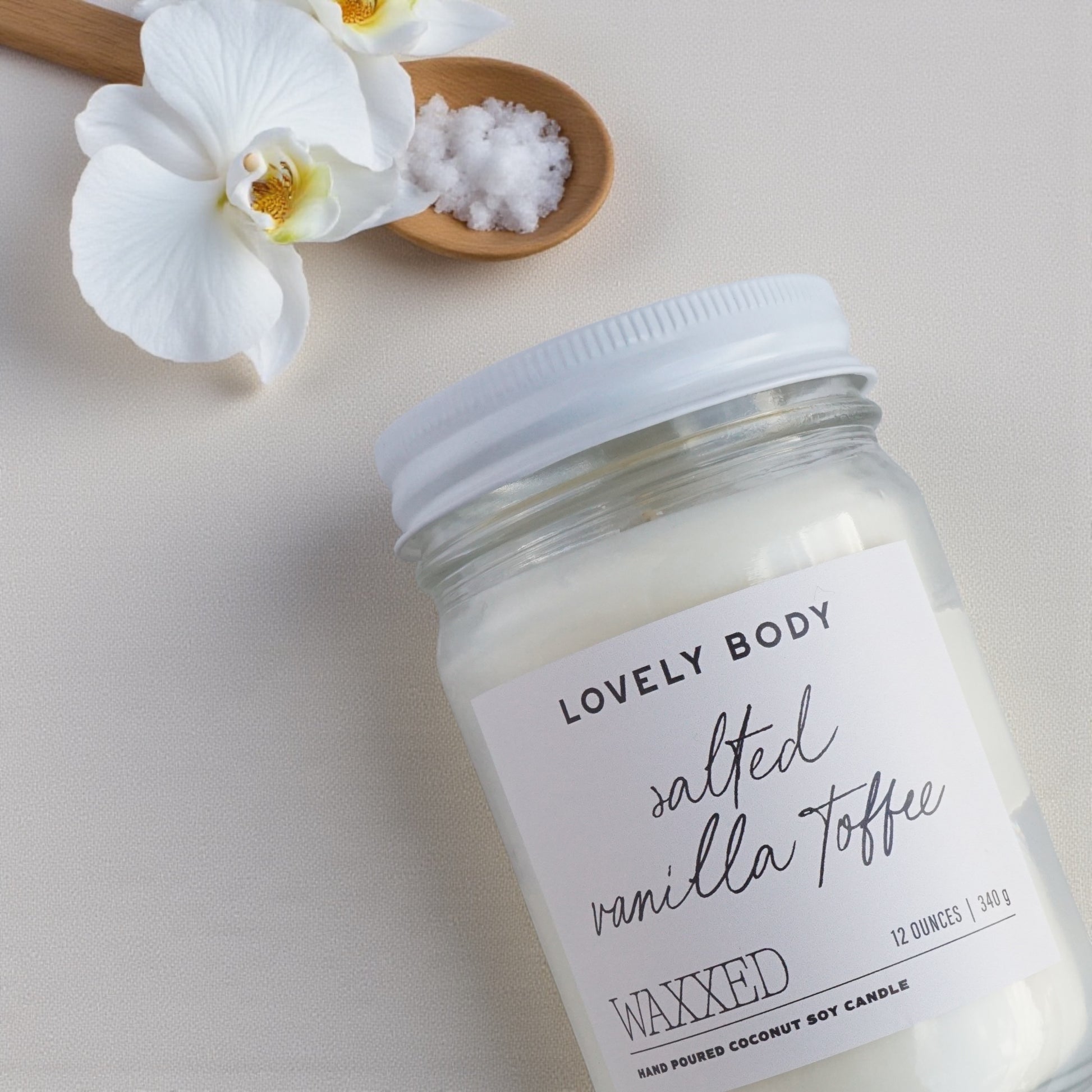 Jar of 'Salted Vanilla Toffee' wax on a light background with flowers and salt.