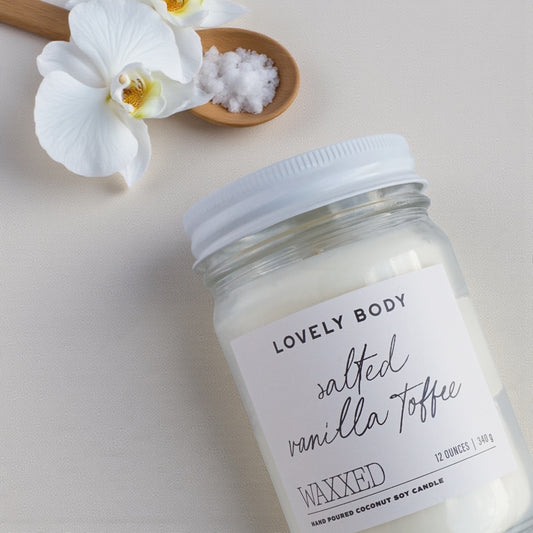 Jar of 'Salted Vanilla Toffee' wax on a light background with flowers and salt.