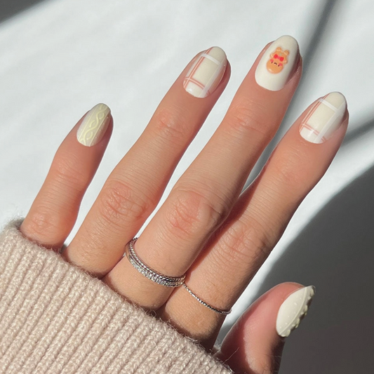 Hand with beige nail polish and a textured sleeve on a neutral background