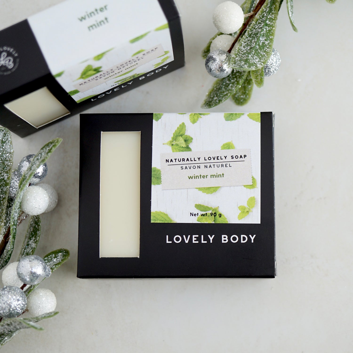 two boxes of soap with green labels, surrounded by sparkling leaves